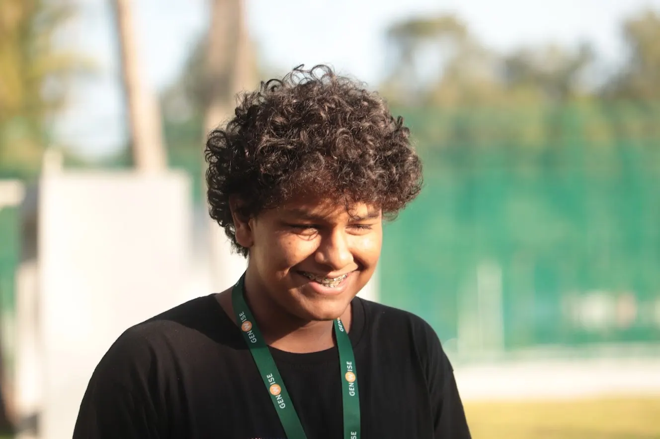 A smiling GenWise student in a GenWise lanyard on the sports field
