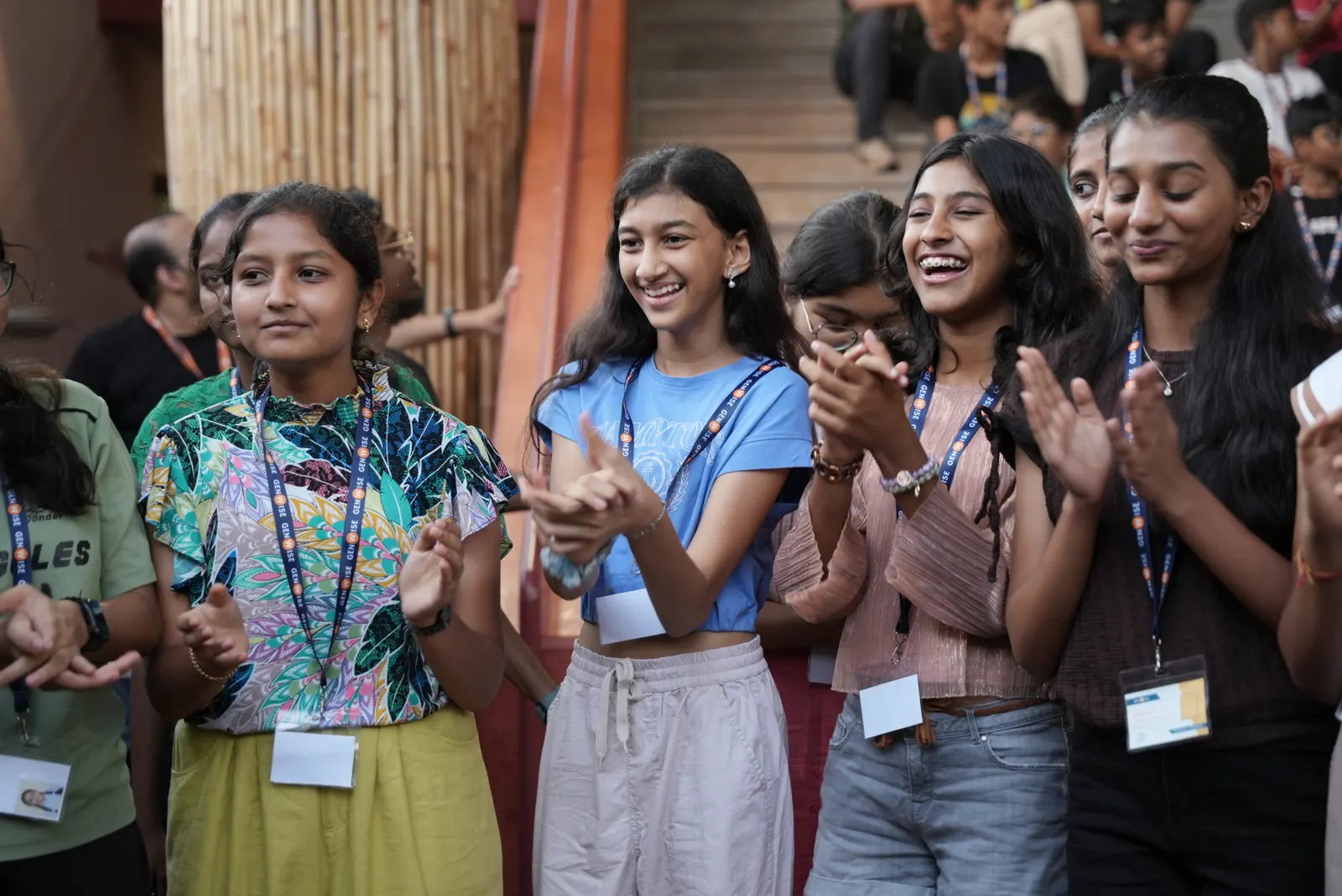 A crowd of GenWise students laughing and clapping at an evening event