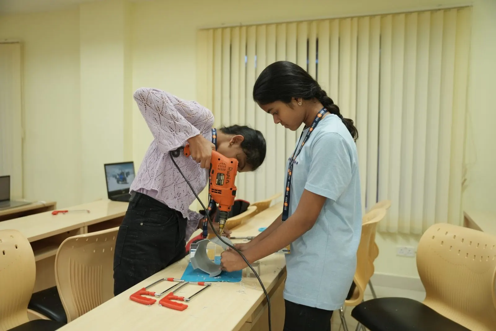 Two GenWise students drilling parts for their engineering build in the classroom