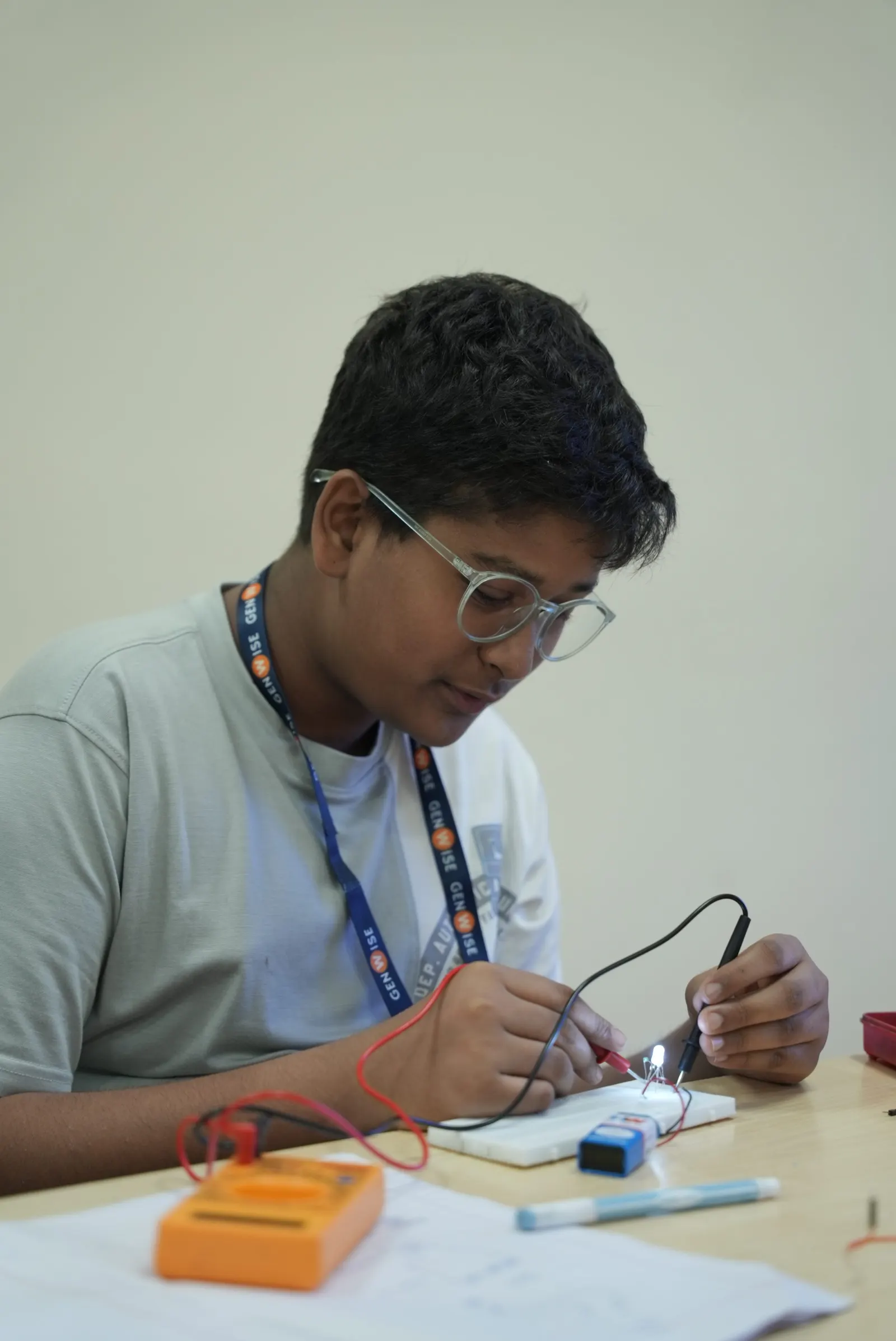 A GenWise student lighting an LED with multimeter probes on a circuit board