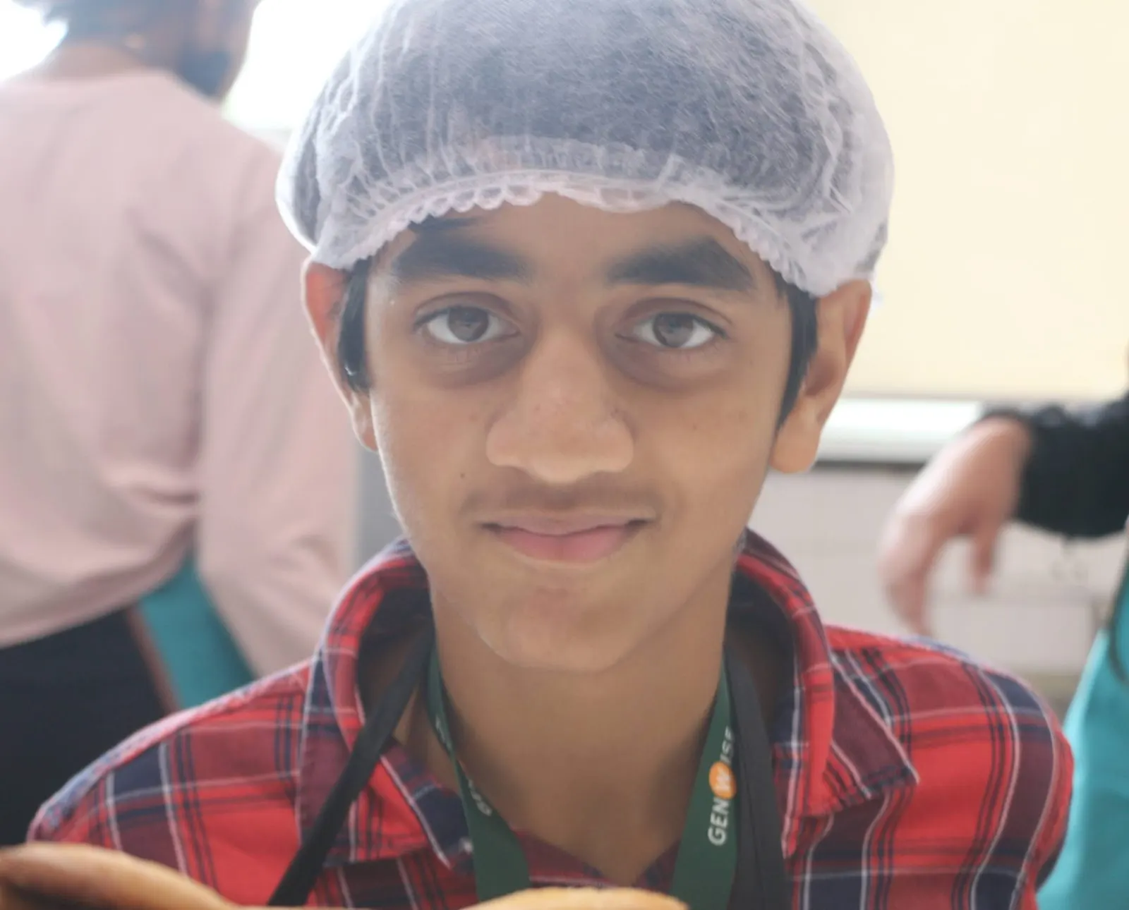 A GenWise student in a hairnet grinning during a baking activity